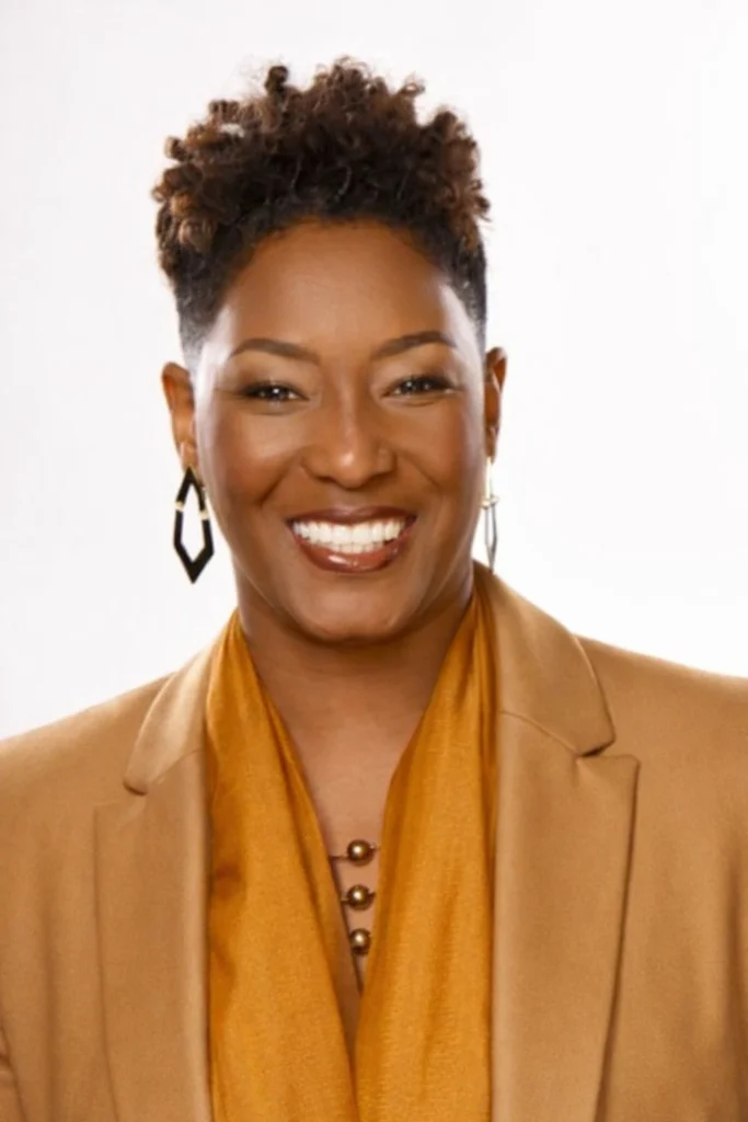 portrait of Risha Grant wearing an orange blouse and tan jacket.